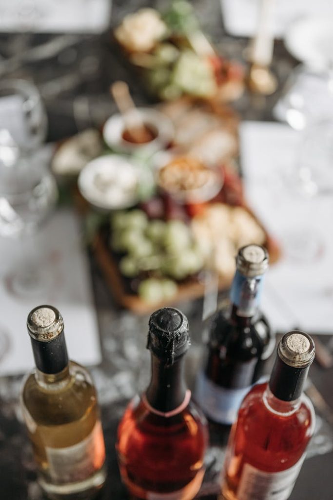 selective-focus-photography-of-wine-bottles-on-table-8775051 Bottles of wine on a table with a blurred background of gourmet appetizers, creating a sophisticated dining ambiance.